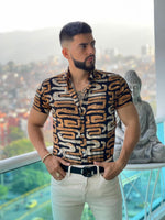 A man wearing a short sleeve shirt with a geometric pattern in brown, and beige colors.