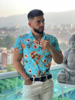 A man wearing a short sleeve shirt with a floral pattern in blue, brown.