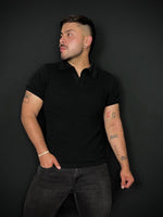 Man wearing a black Chillout polo shirt and black trousers against a black background. Bezurvan.com